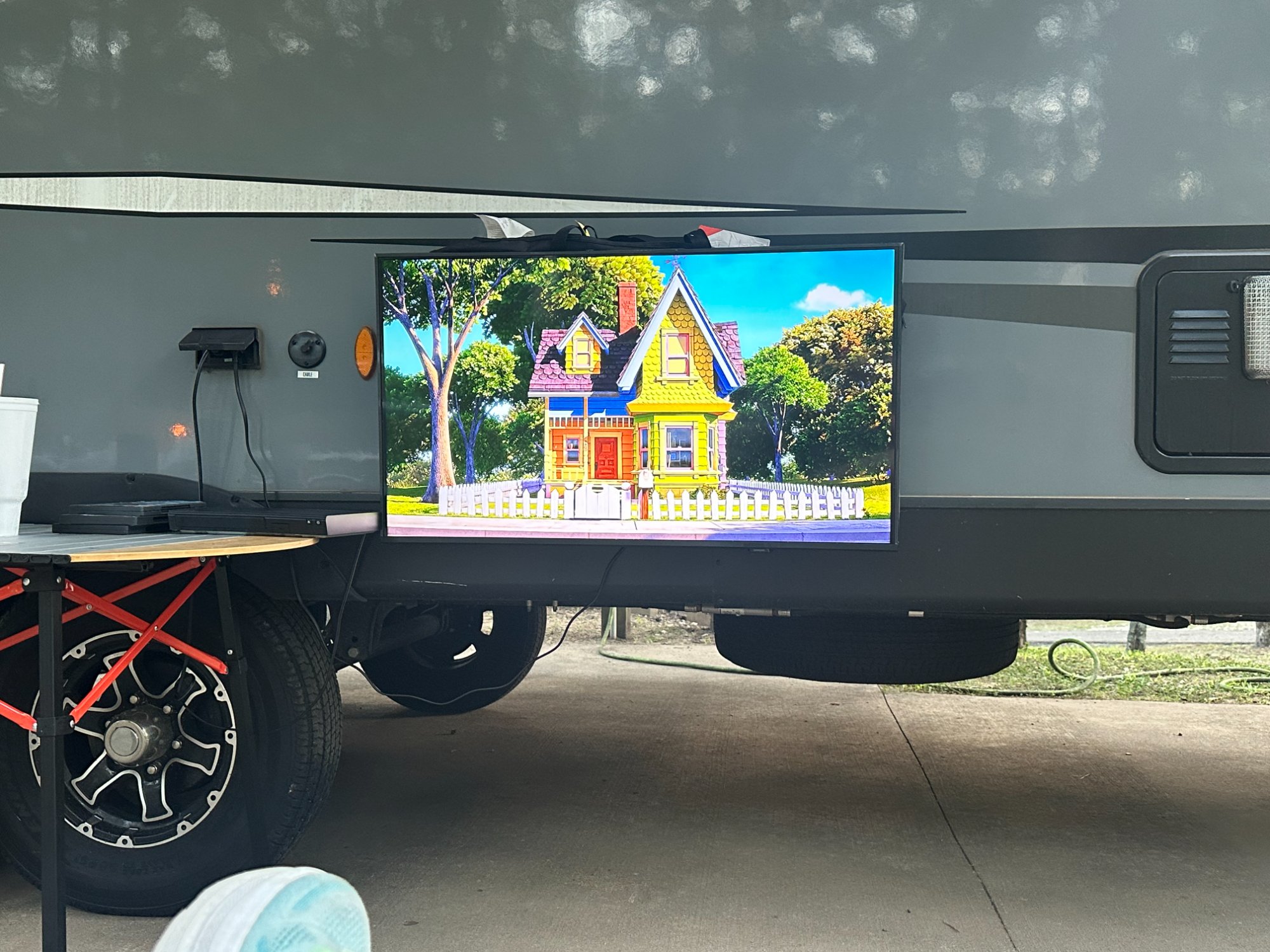 Large outdoor TV mounted on RV with Lippert table nearby for the entertainment setup